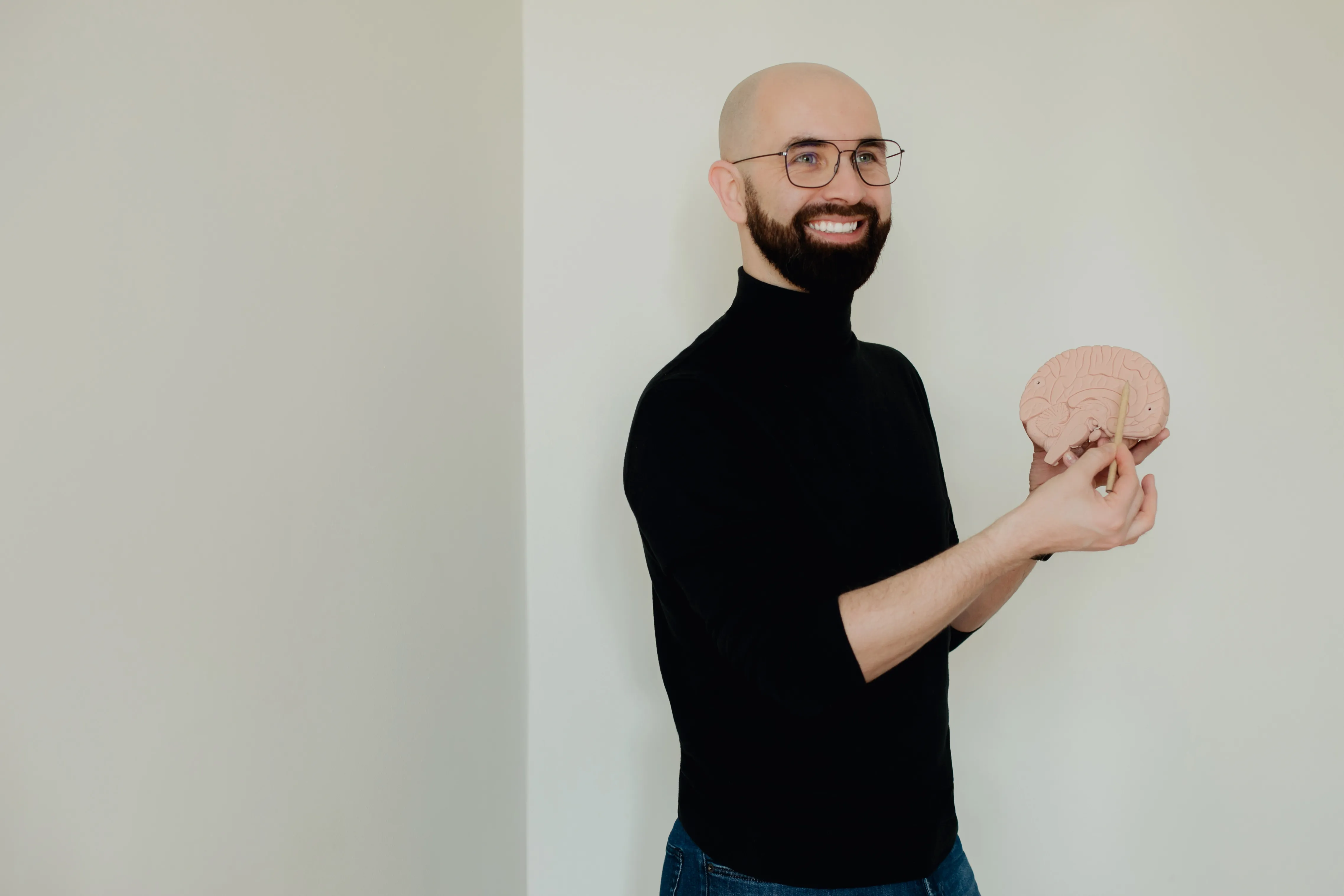 Łukasz Warchoł z uśmiechem, trzymający model mózgu